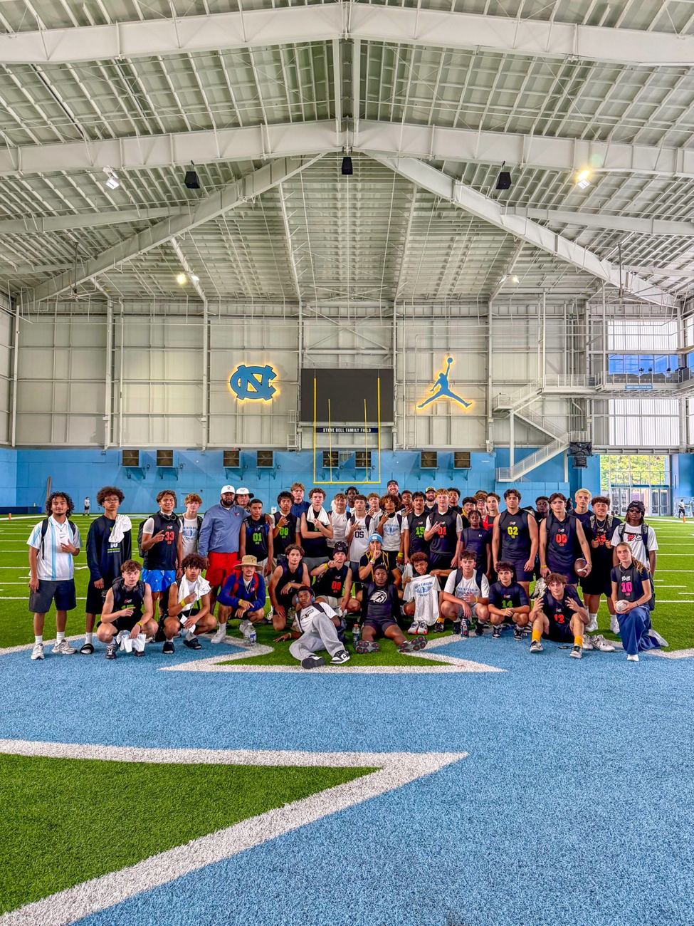 TOUR athletes in UNC's indoor practice facility under the NC logo